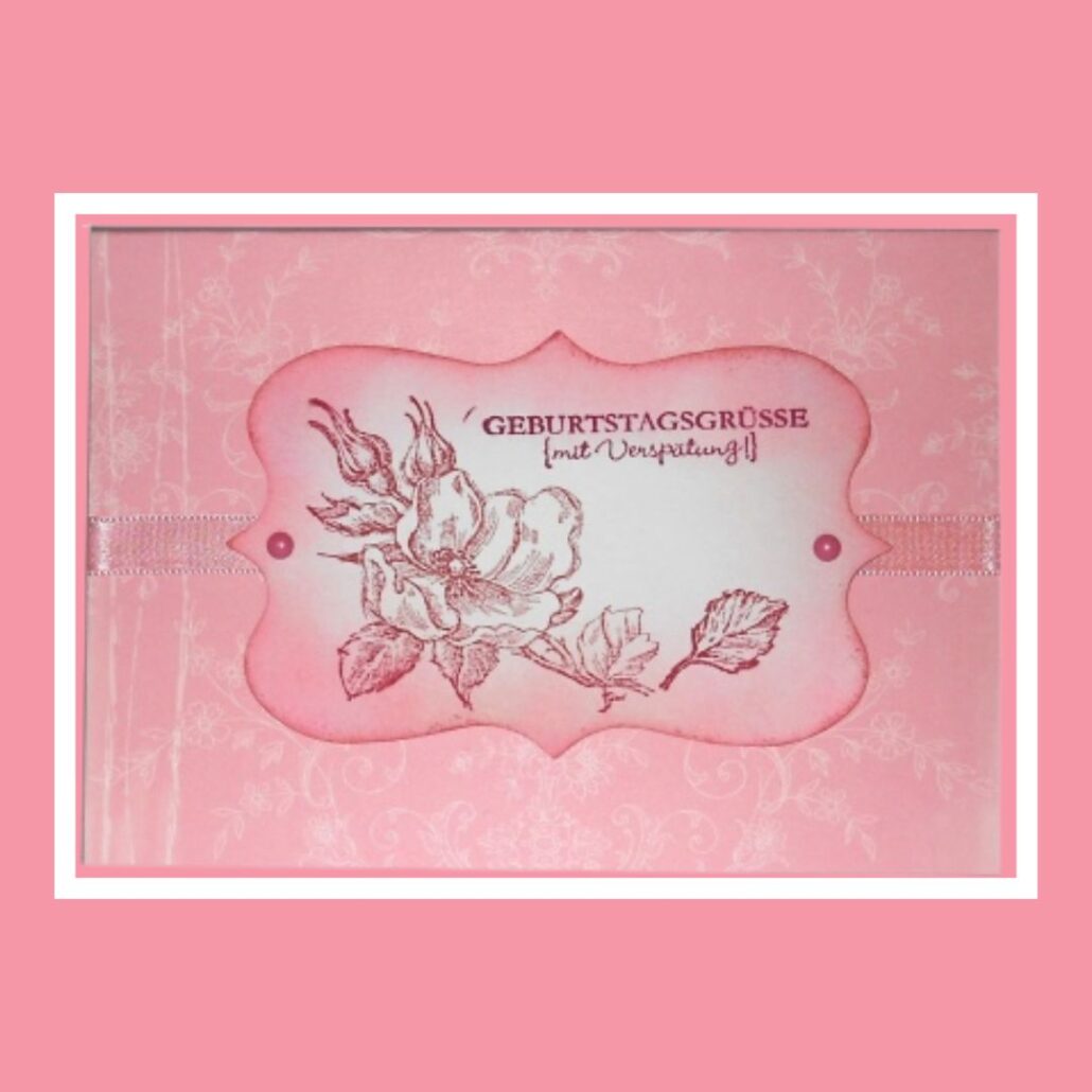 Rosafarbene Geburtstagskarte mit dem Text „Geburtstagsgrüße mit Verspätung“ und einer Blumenillustration in der Mitte, inspiriert von Designs des Blogs Stempelstudio Bergedorf.