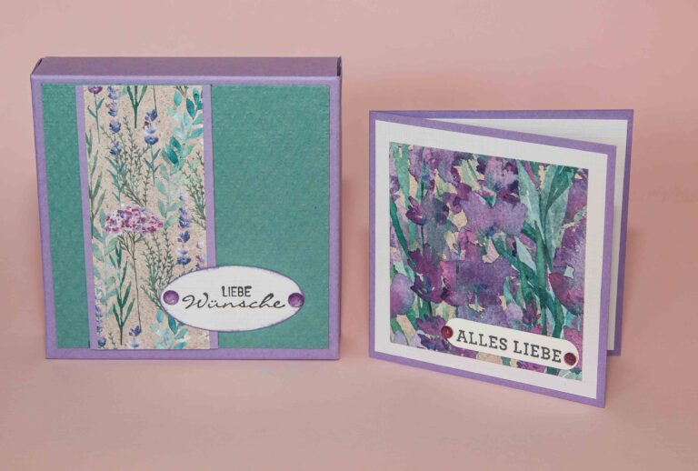 Zwei handgemachte Grußkarten auf rosa Hintergrund, eine mit floralem Druck und ovalem Etikett mit der Aufschrift „liebe wünsche“, die andere mit der Aufschrift „Mach was draus 24. April“.