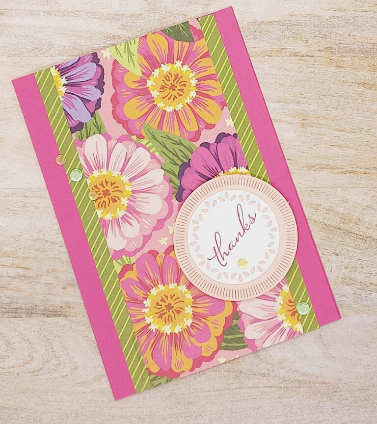 Eine rosa Dankeskarte mit bunten Blumenmustern und grün gestreiften Rändern liegt auf einer Holzoberfläche und erinnert uns daran, am 24. Mai „Mach was draus“ zu machen.