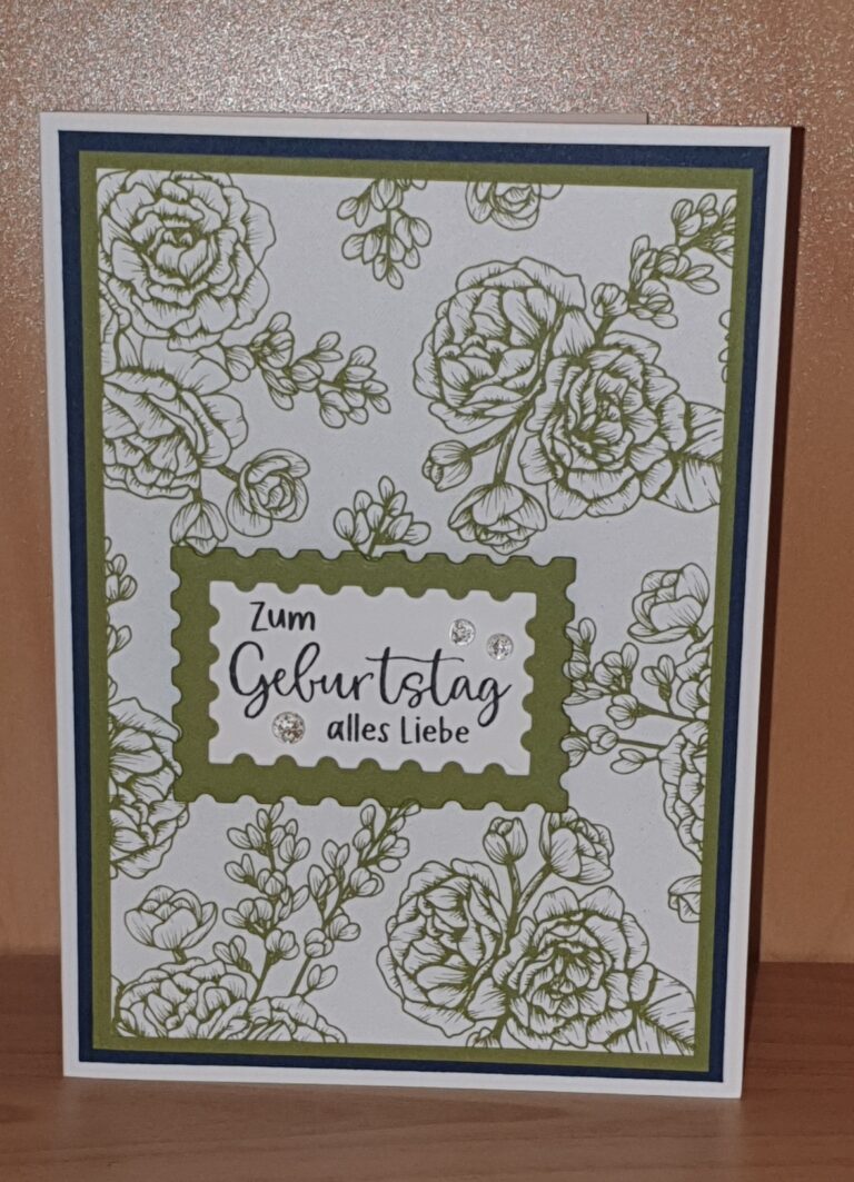 Am 25. April erschien eine deutsche Geburtstagskarte von Mach mit grünen Blumenillustrationen und dem Text „Zum Geburtstag alles Liebe“ in der Mitte, aufrecht auf einer Holzoberfläche ausgestellt.