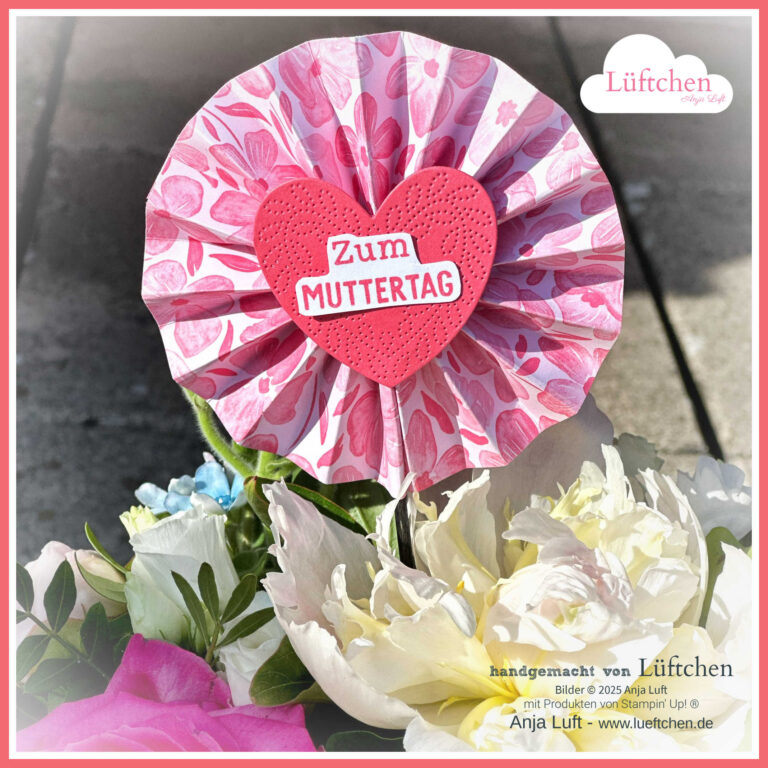 Eine Papierrosette mit einem herzförmigen Herz und der Aufschrift „Zum Muttertag“ ist zwischen bunten Blumen platziert und trägt den Schriftzug „InColor 2025 – 27 Stempelnd durchs Jahr“. Das Lüftchen-Branding und der Urhebernamen erscheinen auf dem Bild. Rhabarberrot