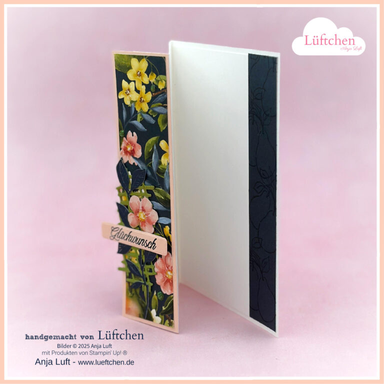 Eine handgefertigte Grußkarte steht offen, mit einem floralen Muster auf der linken Seite, einem "Glückwunsch"-Schriftzug und Akzenten, die von Beste Birnen inspiriert sind. Die schlichte weiße Innenseite kontrastiert mit dem dunklen, dezenten Muster auf der rechten Seite.