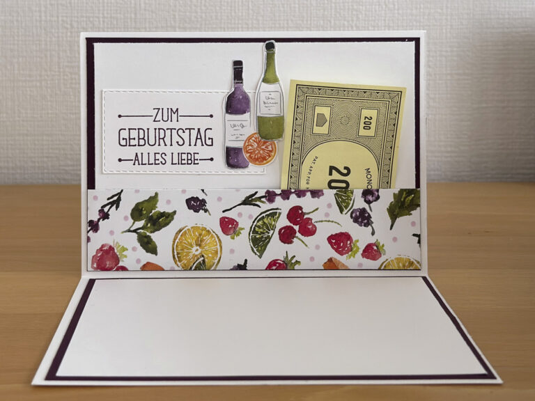 Eine handgemachte Geburtstagskarte, verziert mit Bildern von Weinflaschen, Früchten, einem Monopoly 200-Schein und dem deutschen Text „Zum Geburtstag alles Liebe“ – perfekt für alle, die mit „Mach was draus, 25. Mai“-Inspiration feiern.