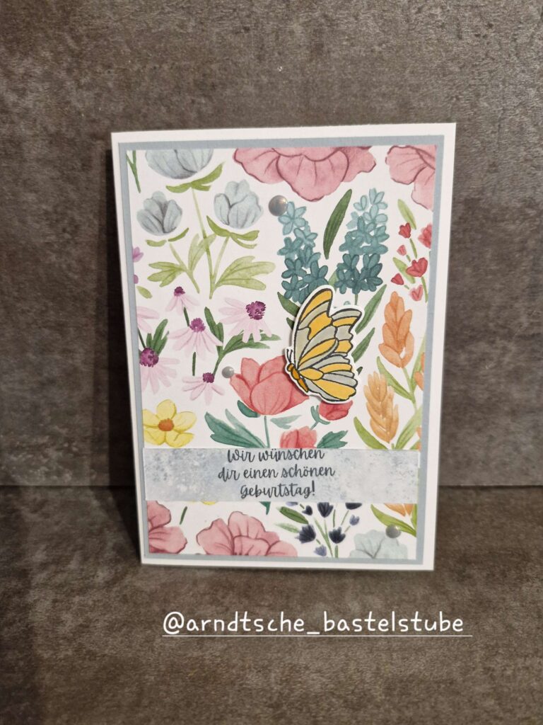 Eine handgefertigte Geburtstagskarte mit bunten Blumenillustrationen und einem Schmetterling, mit dem deutschen Text "Wir wünschen dir einen schönen Geburtstag!", inspiriert von Mach was draus 25. Juni.