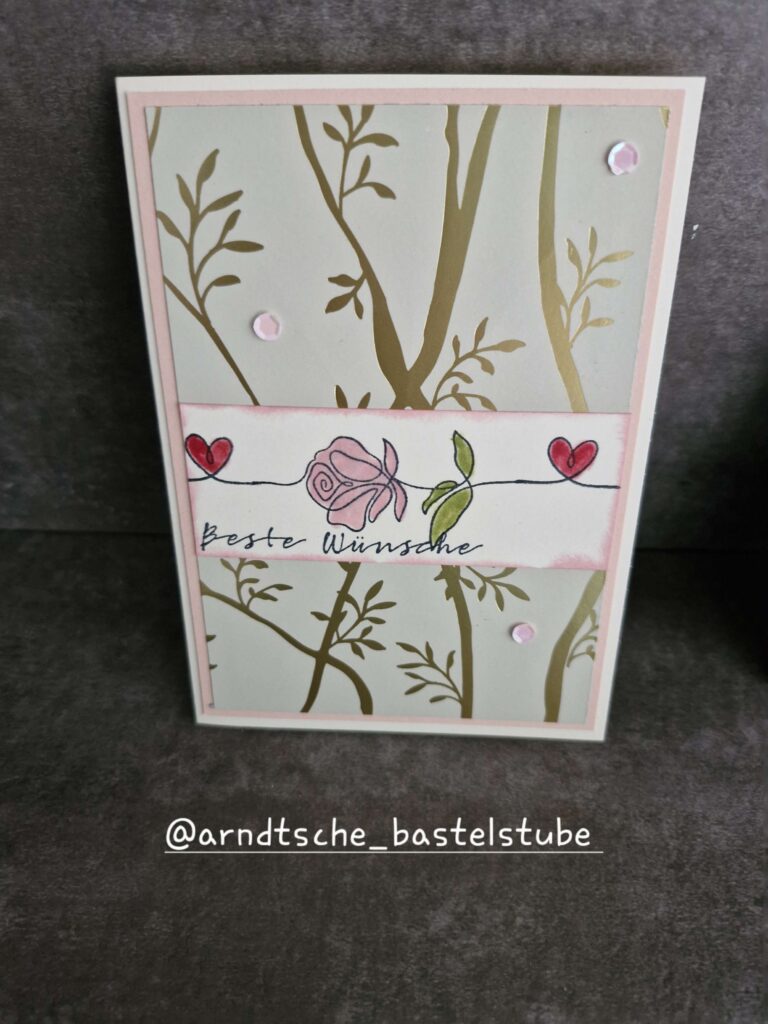 Eine handgefertigte Grußkarte von Mach wurde am 25. Juli draus, mit einem floralen und blättrigen Design, mit einer Rose, zwei Herzen und den Worten "Beste Wünsche" auf der Vorderseite.