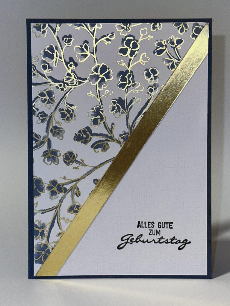 Grußkarte mit einem floralen Muster in Gold und Blau oben links, einem diagonalen Goldstreifen und dem deutschen Text "Alles Gute zum Geburtstag" unten rechts - inspiriert von Mach was draus 25. Juli.