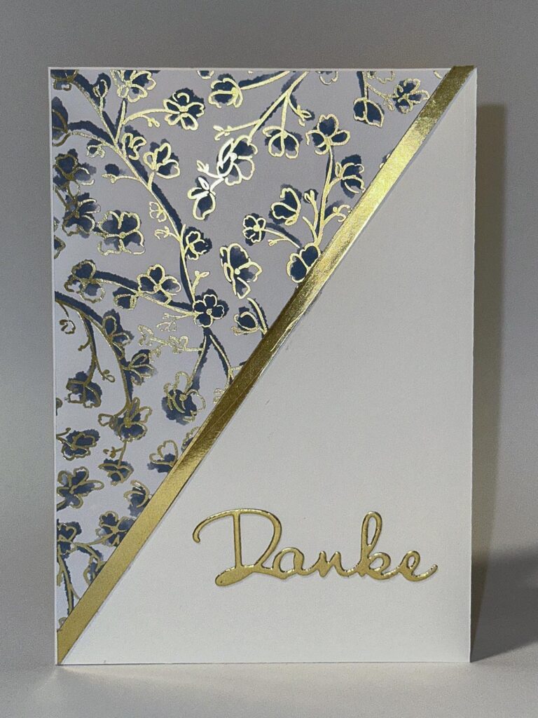 Eine Grußkarte mit goldenen Blumenmustern oben links und "Danke" in goldener Schrift unten rechts, getrennt durch eine diagonale goldene Linie - perfekt für Ihr Mach was draus 25 Kreativprojekt.