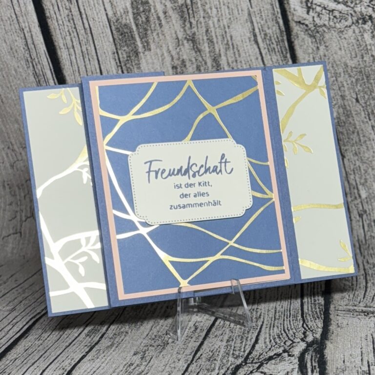 Eine dekorative Karte auf einem Ständer mit goldenen abstrakten Linien und dem deutschen Text: "Freundschaft ist der Kitt, der alles zusammenhält." Perfekt als Inspiration für dein nächstes Mach was draus Juli 25 Projekt.