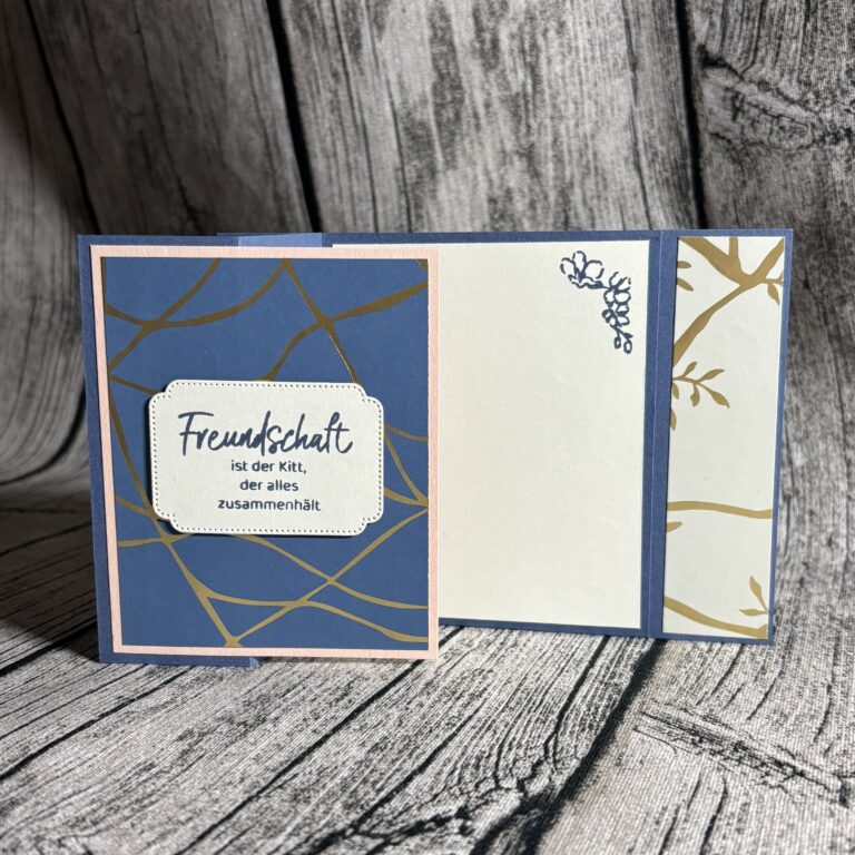 Eine handgefertigte Karte mit abstrakten Motiven in Blau, Weiß und Gold, die für Mach was draus am 25. Juli erstellt wurde, trägt auf der Vorderseite den deutschen Text "Freundschaft ist der Kitt, der alles zusammenhält.
