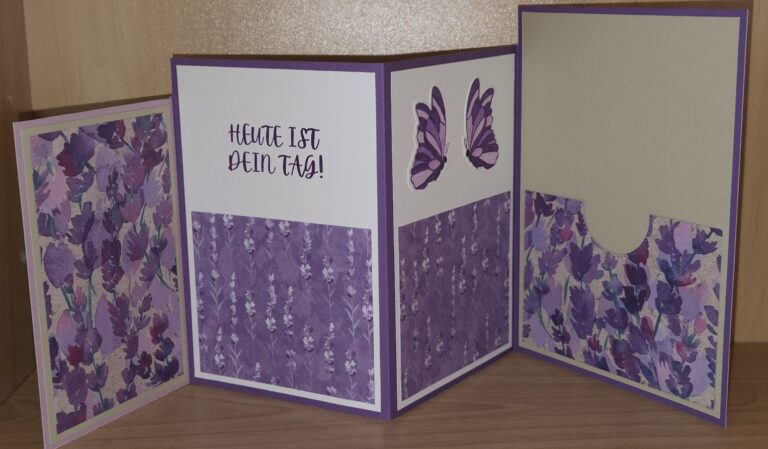 Eine handgefertigte lila-weiße Klappkarte mit Blumenmustern, einem Schmetterlingsausschnitt, einer Tasche und dem deutschen Text "HEUTE IST DEIN TAG!" in der Mitte - perfekt für Mach war draus 25. August.