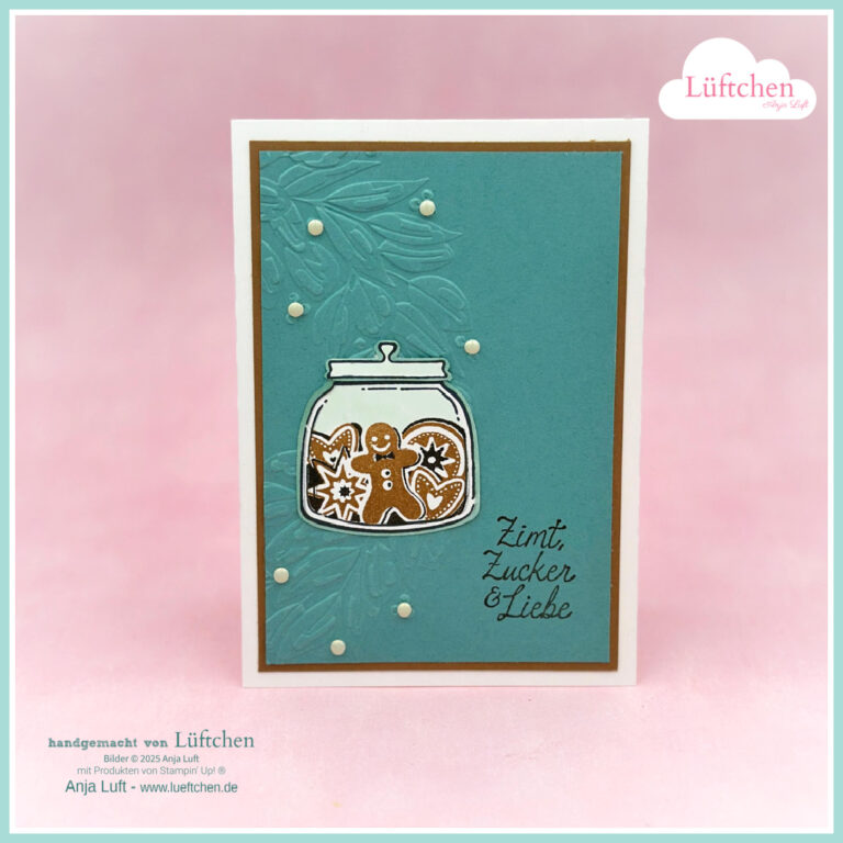 Eine handgefertigte Grußkarte mit einem Glas mit einem Lebkuchenmann und dem Text "Zimt, Zucker & Liebe"-Weihnachtsfreude im Glas- auf einem tealfarbenen Hintergrund mit geprägten Blättern und weißen Punktverzierungen.