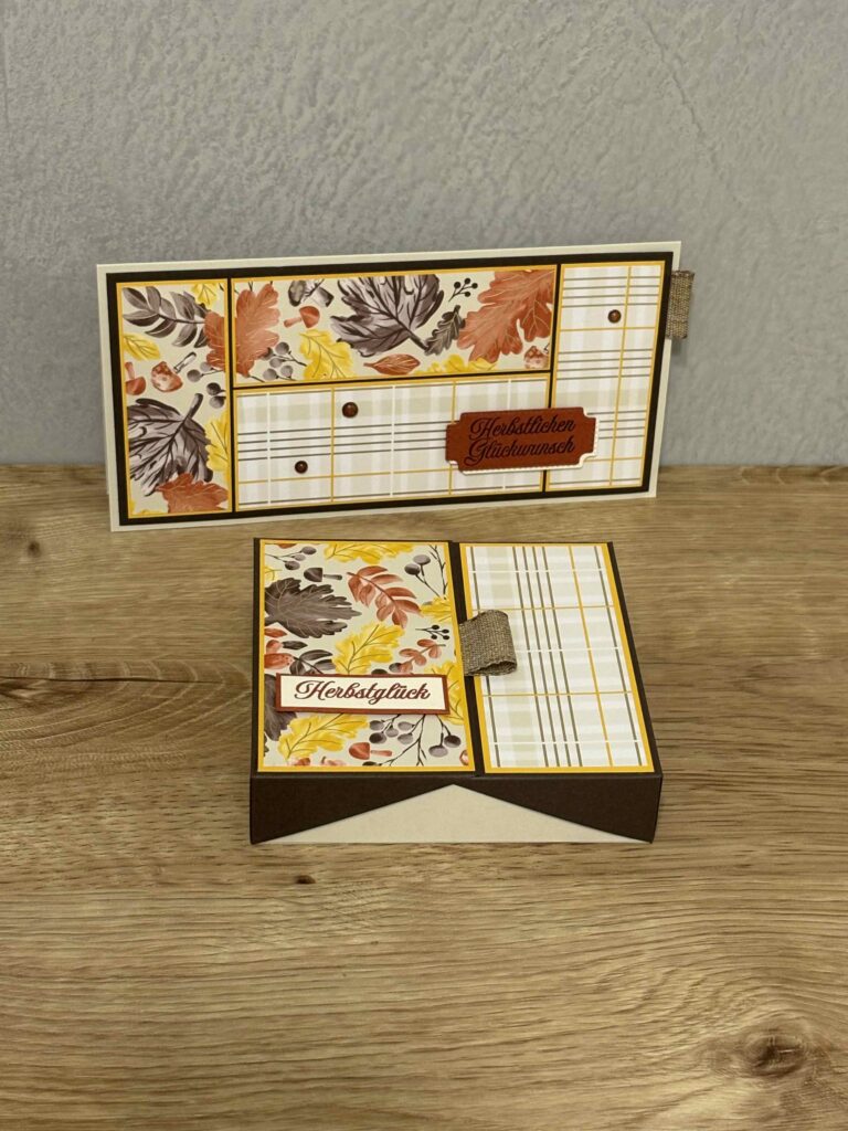 Eine handgefertigte herbstliche Grußkarte und die dazugehörige Schachtel, verziert mit Herbstblättern und deutschem Text, inspiriert von Mach was draus am 25. September, werden auf einer Holzfläche ausgestellt.