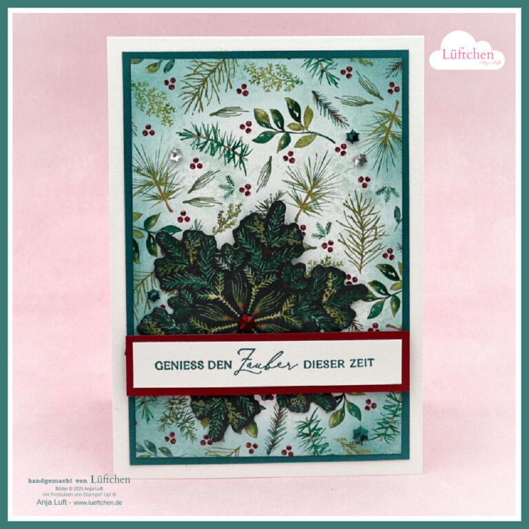 Eine handgefertigte Weihnachtskarte mit grünem und rotem Tannenmotiv, einer mehrschichtigen Stechpalmenverzierung und dem deutschen Text "GENIESS DEN ZAUBER DIESER ZEIT" auf einem weißen Banner - perfekt für Mach was draus 25. Oktober.