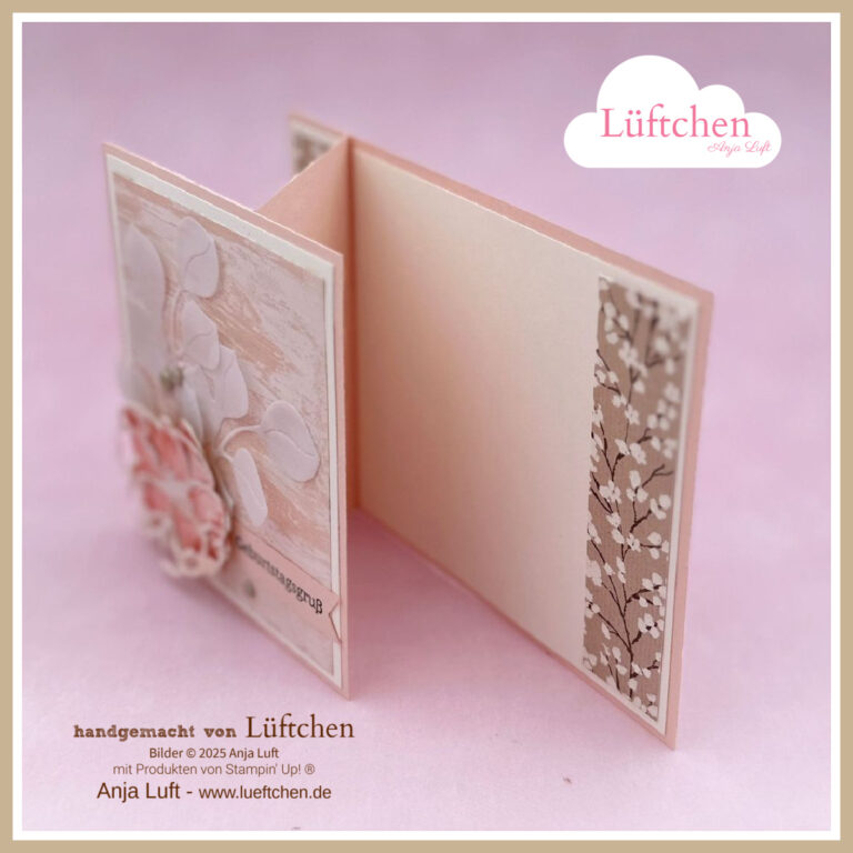 Eine handgefertigte Grußkarte mit Blumendekoration und gemustertem Papier, die teilweise geöffnet ist, um das Innere zu enthüllen, wird vor einem zartrosa Hintergrund präsentiert - eine echte Petals of Beauty-Kreation.