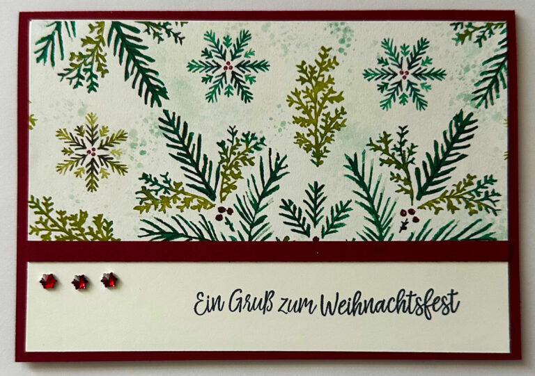 Eine Weihnachtskarte mit grünen Tannenzweigen und Schneeflocken, drei kleinen roten Edelsteinen und dem deutschen Text "Ein Gruß zum Weihnachtsfest" - ein festliches Projekt, das von Mach was draus 25. Oktober inspiriert wurde.