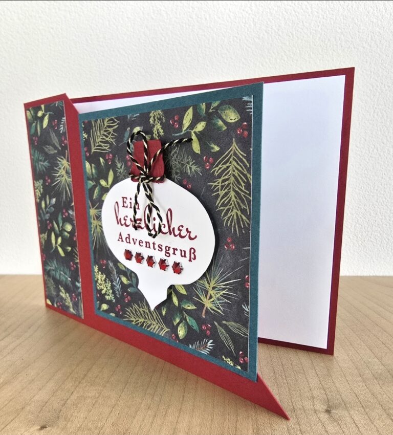 Eine handgefertigte Weihnachtskarte von Mach wurde am 25. Oktober draus, mit einer roten Umrandung, Tannen- und Beerenmustern und einem weißen Anhänger in Form eines Ornaments mit deutschem Text, der mit einer schwarz-weißen Schnurschleife gebunden wurde.