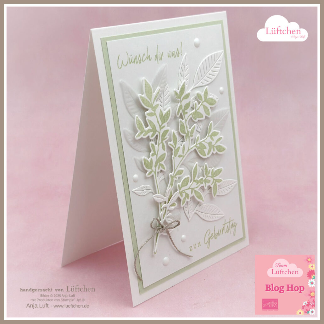 Eine handgefertigte Geburtstagskarte mit grünen und weißen Blattmotiven aus dem neuen Katalog, mit deutschem Text und Zierperlen, aufrecht stehend auf rosa Hintergrund.