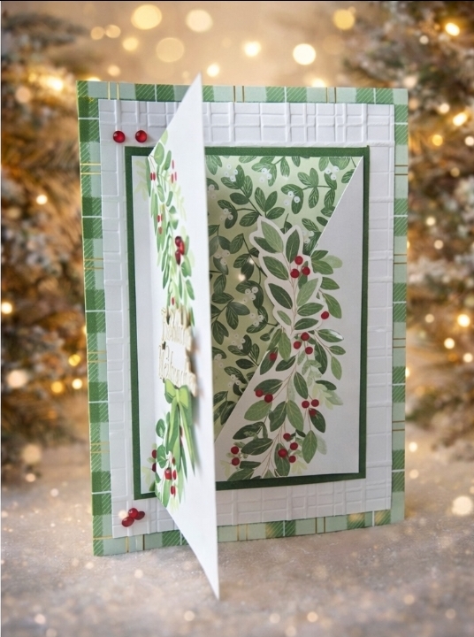 Eine handgefertigte Festtagskarte mit grünem und weißem Blattmuster, akzentuiert durch rote Beeren, teilweise geöffnet, vor einem verschwommenen festlichen Hintergrund mit Lichtern und Bäumen - perfekt für Mach was draus am 25. Dezember.