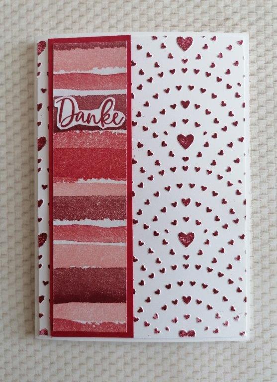 Eine Grußkarte mit roten und rosafarbenen Querstreifen auf der linken Seite, dem Text "Danke" und einem Muster aus roten Herzen in Bögen auf der rechten Seite - perfekt für Mach was draus 26. Januar.