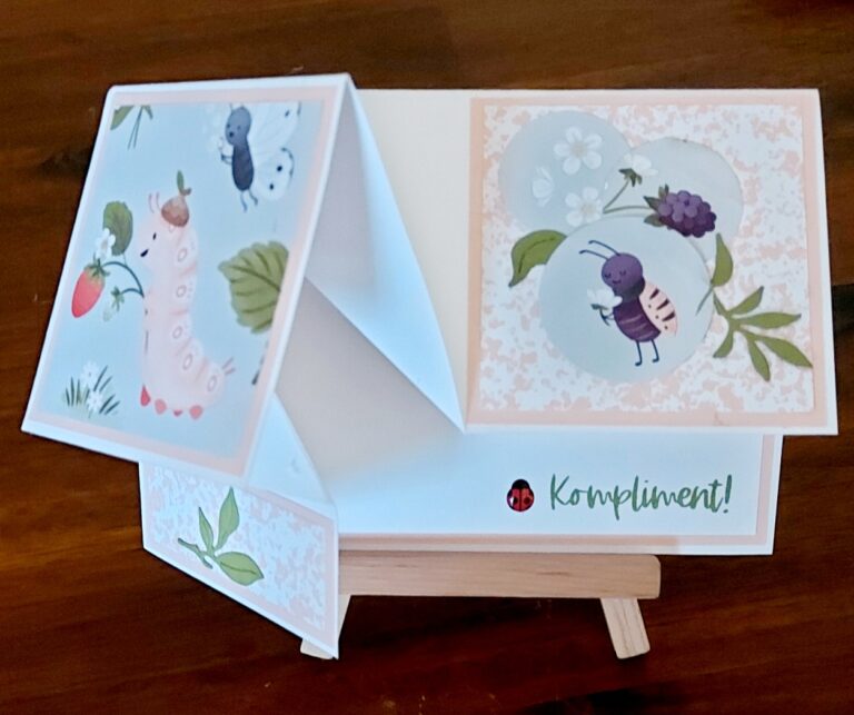 Handgefertigte, gefaltete Grußkarte mit "Kompliment!", einer Marienkäfergrafik und charmanten Illustrationen einer Raupe, die eine Erdbeere isst, einer Ameise und Blättern. Teil der Mach was draus 26 Februar Kollektion.