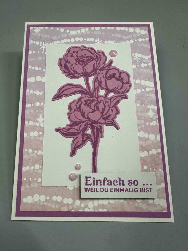 Eine handgemachte Karte, inspiriert von Mach was draus 26. März, mit einem rosa Blumenmuster und dem deutschen Text "Einfach so ... WEIL DU EINMALIG BIST" auf einem lilafarbenen, gemusterten Hintergrund mit Farbverlauf.