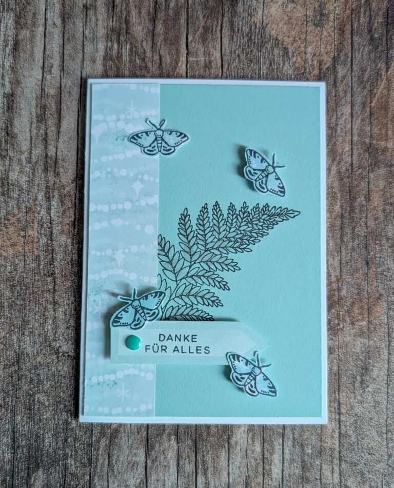 Eine handgefertigte Karte mit Schmetterlings- und Farnmotiven, hellblauem Hintergrund und einem "Danke für alles"-Schriftzug auf einer Holzoberfläche - erstellt für Mach was draus 26. März.