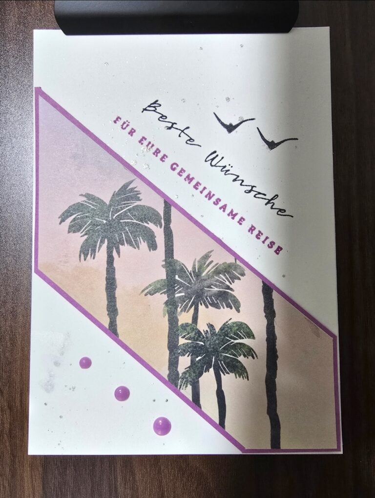 Eine Grußkarte von Mach was draus März 26 zeigt Palmen, zwei Vögel und den deutschen Text "Beste Wünsche für eine gemeinsame Reise" auf hellem Hintergrund mit lila Akzenten.