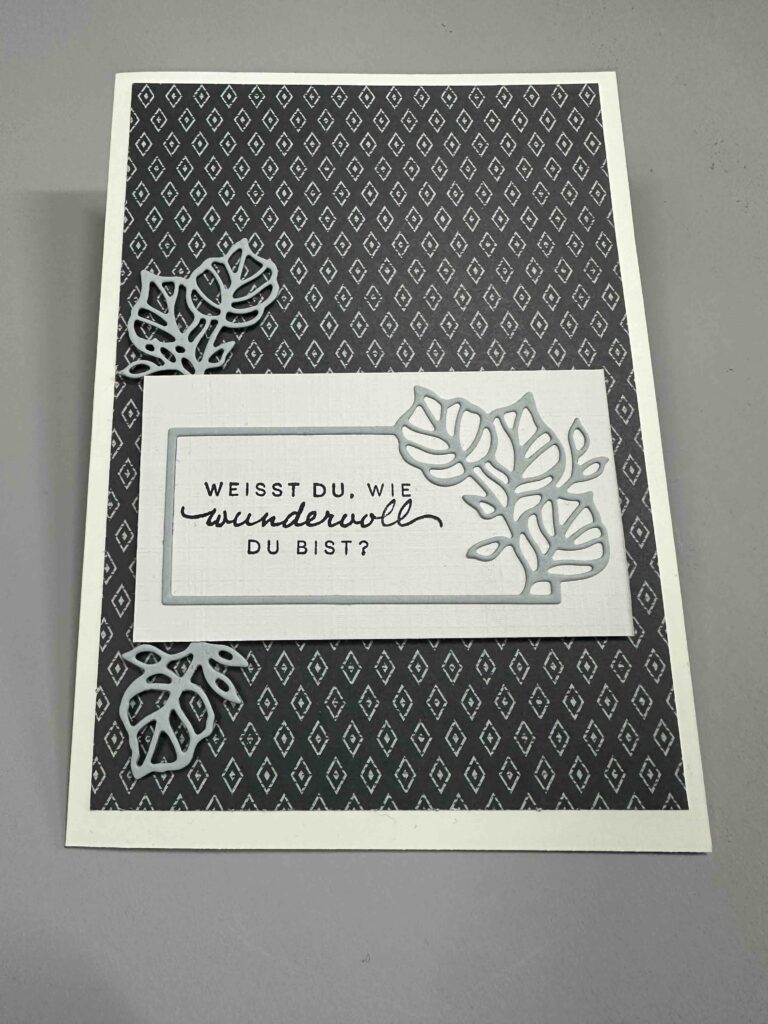 Eine Grußkarte mit einem schwarz-weiß gemusterten Hintergrund, weißen ausgeschnittenen Blättern und dem deutschen Text "Weisst du, wie wundervoll du bist?" - perfekt für Mach war draus 26. April.