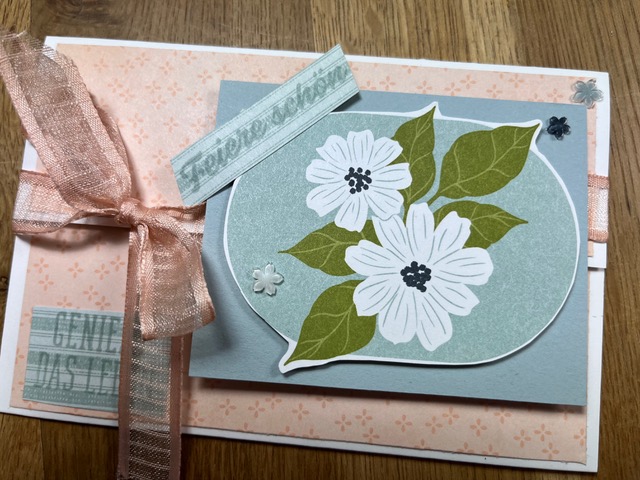 Eine handgefertigte Grußkarte mit rosafarbener Schleife, Blumenmuster und deutschem Text "Gute Besserung" und "Genesungswünsche" auf einer Holzoberfläche - perfekt für Mach war draus 26. April Projekte.