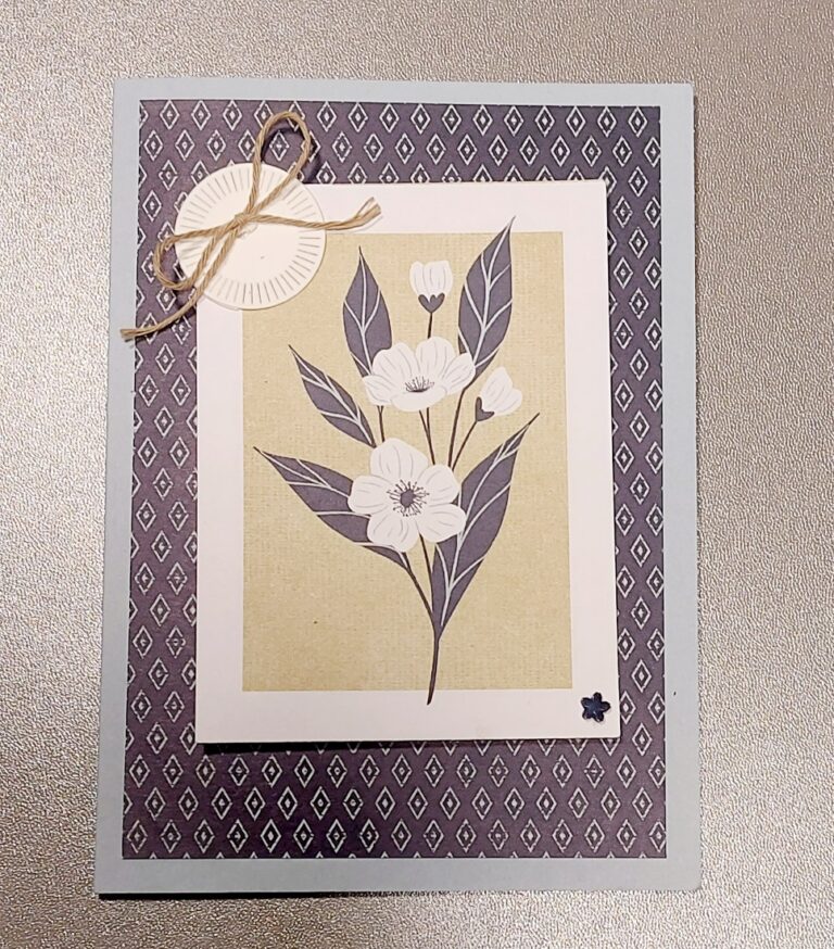 Eine Grußkarte mit einer einfachen Illustration weißer Blumen mit grauen Blättern, einem geometrisch gemusterten Rand und einer kleinen Schleife in der linken oberen Ecke - perfekt für Mach war draus 26. April.