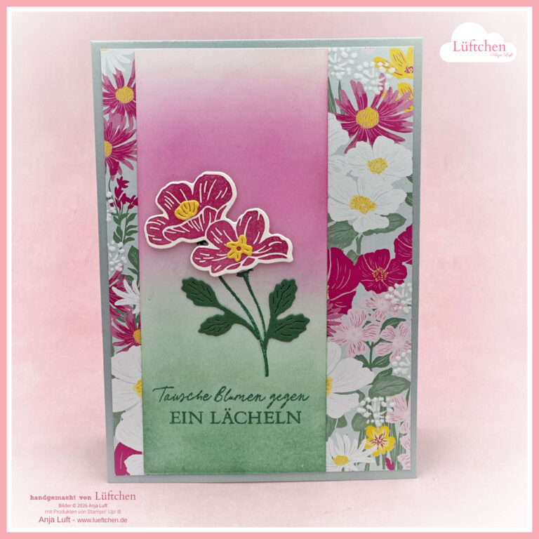 Eine handgefertigte Grußkarte mit floralen Motiven, die rosa und gelbe Blumen und den deutschen Text "Tausche Blumen gegen EIN LÄCHELN" auf einem Hintergrund mit rosa und grünem Farbverlauf zeigt. Entdecken Sie jetzt unsere Neuen Produkte - Mai 2026!.
