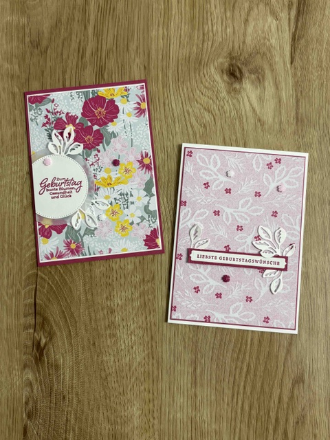 Zwei handgefertigte Geburtstagskarten auf Holzunterlage; Teil der Serie „Mach war draus“ vom 26. Mai: Eine Karte ist mit bunten Blumenmustern verziert, die andere zeigt ein rosa Blumenmuster mit deutschen Geburtstagsgrüßen.
