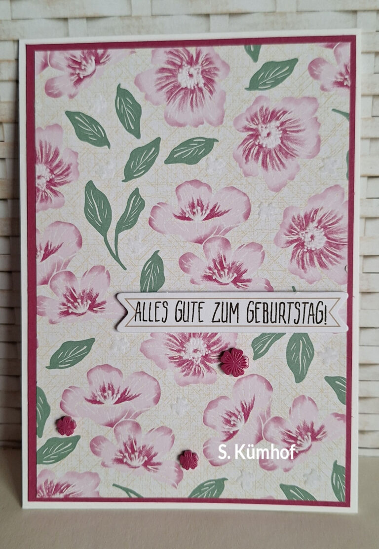 Eine Geburtstagskarte mit rosa Blumen und grünen Blättern, auf der auf einem Banner der deutsche Text „ALLES GUTE ZUM GEBURTSTAG!“ zu lesen ist, in der rechten unteren Ecke „S. Kümhof“ steht und „Mach was draus Mai 26“ dezent in das Design integriert ist.