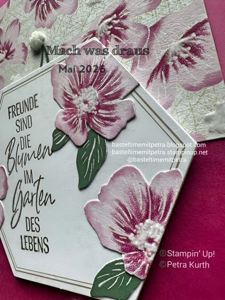 Eine Nahaufnahme einer handgefertigten Karte mit rosa-weißen geprägten Blumen, deutschem Text und Blog-Wasserzeichen auf einem leuchtend rosa Hintergrund für „Mach was draus“ vom 26. Mai.