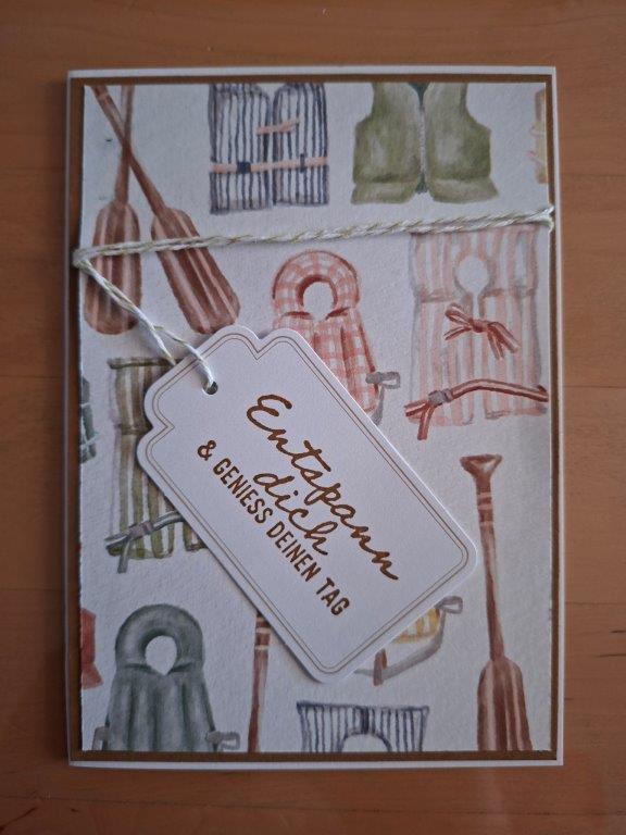Eine Grußkarte mit Motiven von Rudern, Hüten und Stiefeln, mit einer Schnur zusammengebunden und einem Anhänger mit der Aufschrift „Entspann dich & genieß deinen Tag“. Perfekt für eine liebevolle Nachricht oder als Teil deines „Mach was draus“-Projekts vom 26. Juli.