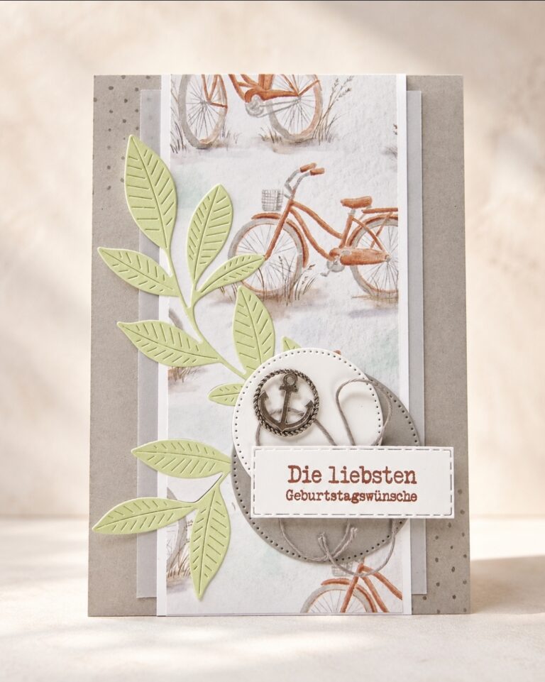 Handgefertigte Geburtstagskarte mit Papier im Fahrrad-Motiv, grünen Blattverzierungen, Metallzahnrädern und einem Etikett mit der Aufschrift „Die liebsten Geburtstagswünsche“ auf Deutsch. Dieses einzigartige Design wurde im Rahmen der „Mach was draus“-Challenge vom 26. Juli liebevoll gestaltet.
