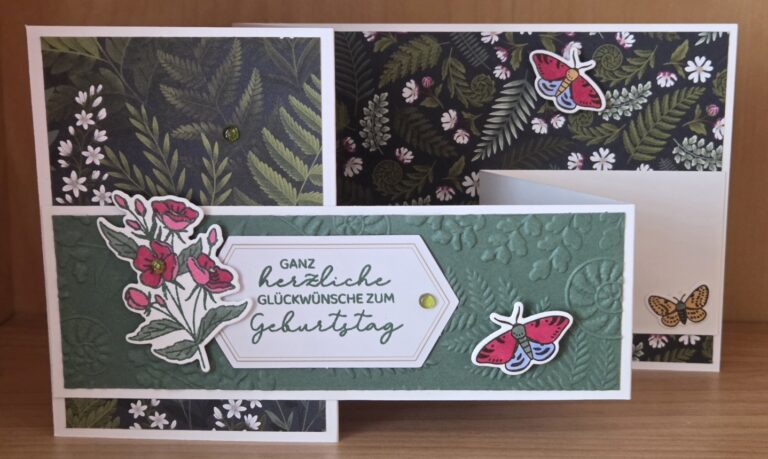 Handgefertigte Geburtstagskarte, inspiriert von Mach was draus vom 26. August, mit geprägtem grünem Papier, Blumen- und Schmetterlingsmotiven sowie dem deutschen Text „Ganz herzliche Glückwünsche zum Geburtstag“ auf einem strahlend weißen Etikett.
