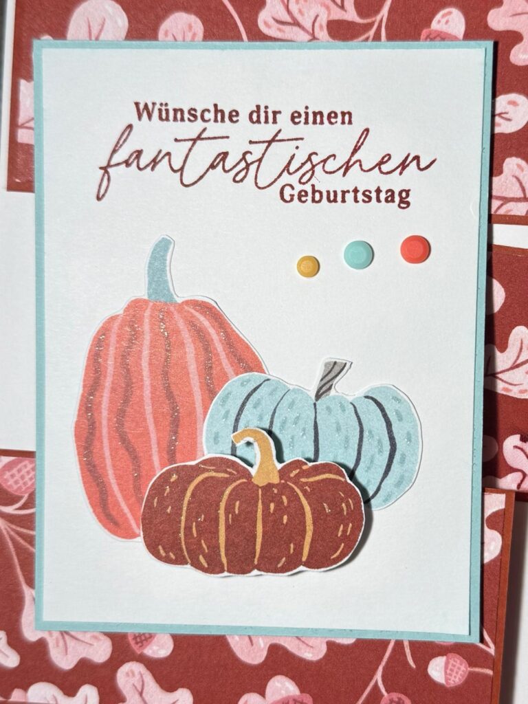 Grußkarte mit drei illustrierten Kürbissen, bunten Punkten und dem Schriftzug „Wünsche dir einen fantastischen Geburtstag“ auf einem Blumenmuster – perfekt für „Mach was draus“ am 26. September.
